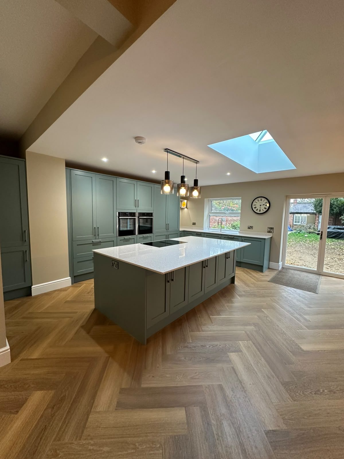 sage green kitchen with island and herringbone floor