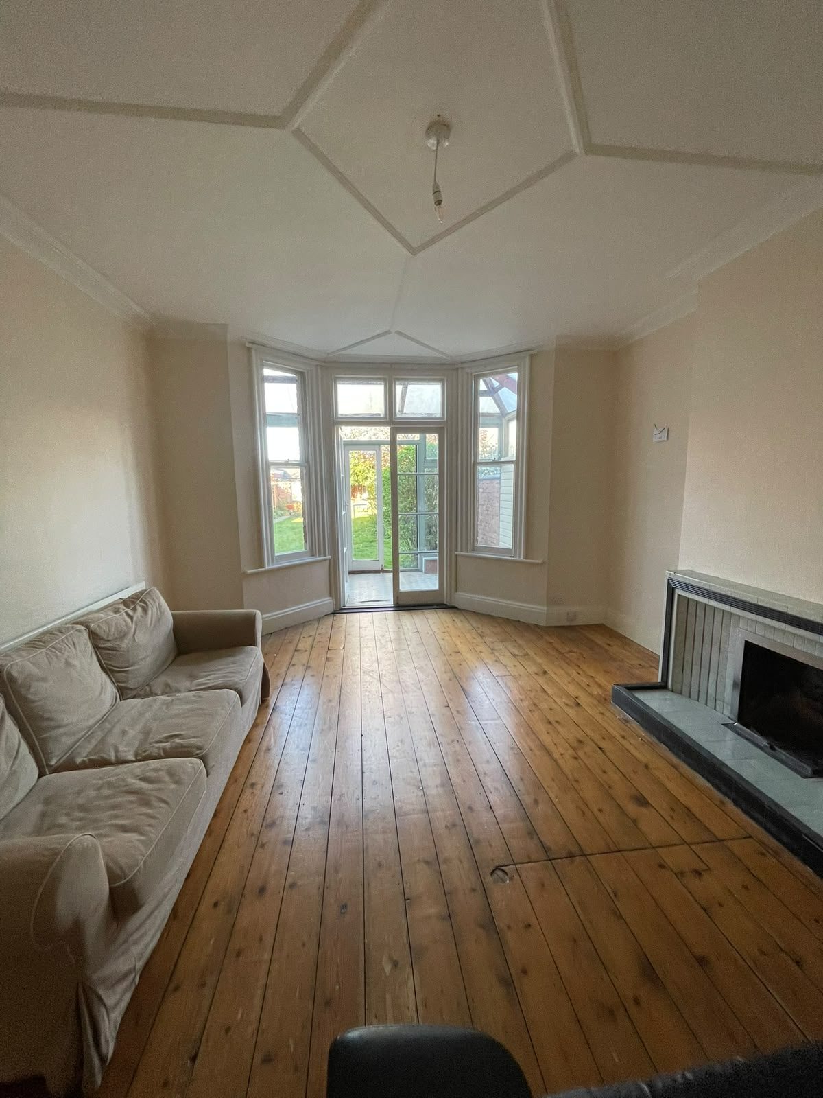 Living room with a bay window, timber floor and fireplace
